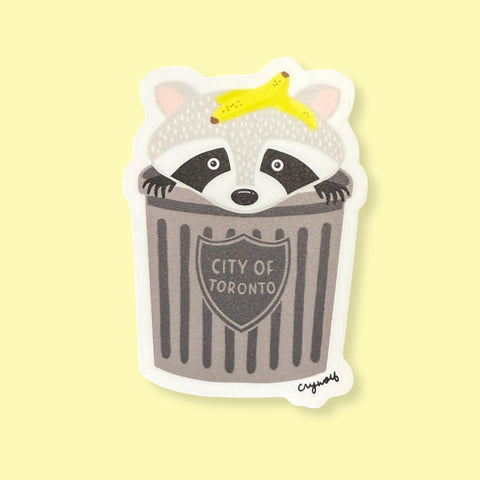 Sticker of a raccoon in a trash can with 'City of Toronto' text on a yellow background